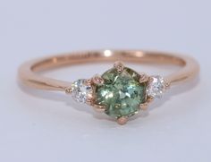 a green and white diamond ring with three diamonds