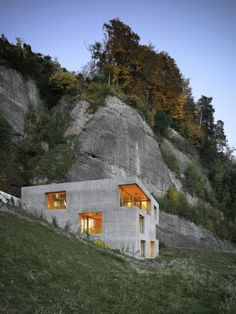 a house built into the side of a mountain with windows lit up at night time