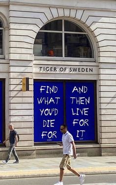 two men walking down the street in front of a building with blue doors that say find what you've live for