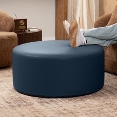 a person sitting on a blue ottoman in a living room next to a brown chair