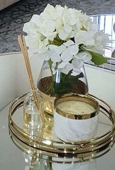 there is a vase with white flowers in it on a glass table next to a mirror