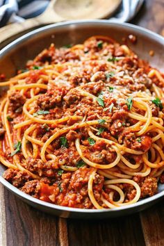 a pan filled with spaghetti and sauce on top of a wooden table