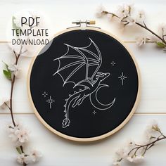 a black and white embroidery pattern with a dragon flying over the moon on it's back