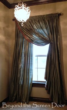 a window with curtains and a chandelier hanging from it