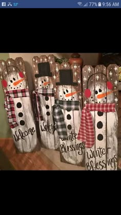 some snowmen are standing next to each other on wooden boards with words painted on them