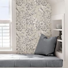 a window seat in front of a wall papered with flowers and leaves on it