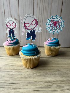 three cupcakes with spiderman decorations on top of them sitting on a table