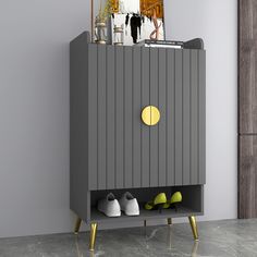 a grey cabinet with shoes on it and a mirror in the corner behind it, next to a pair of green slippers