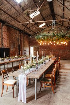 a long table with candles and flowers on it in a large room filled with chairs