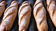 several loaves of bread sitting on top of a black cloth covered in powdered sugar