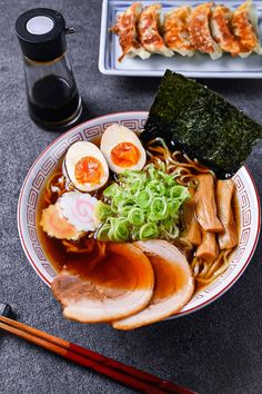 a bowl filled with meat and vegetables next to chopsticks on top of a table