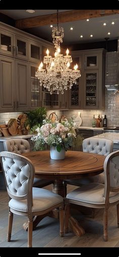 a dining room table with chairs and a chandelier hanging from the ceiling above it