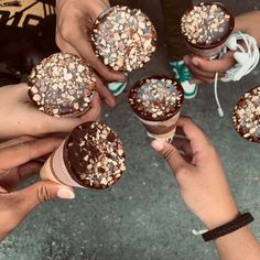 four people holding ice cream cones with sprinkles on them