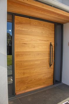 a wooden door is open on the side of a house with glass doors and metal handles