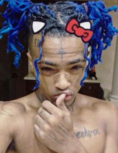 a shirtless man with blue dreadlocks on his head and tongue sticking out