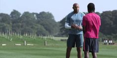 two men standing on top of a lush green field