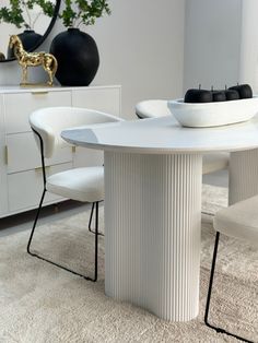 a white dining table with two chairs and a bowl on top of it in a living room