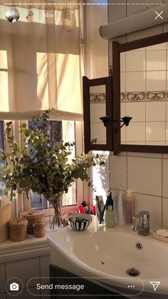 a white sink sitting under a bathroom mirror next to a window with blinds on it