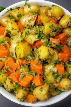 a white bowl filled with potatoes and carrots