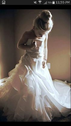 a woman in a white dress is standing on a bed with her hands behind her back