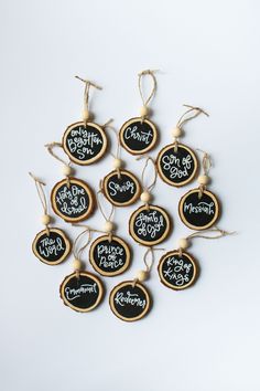 six christmas ornaments with chalkboard sayings hanging from twine string on white background