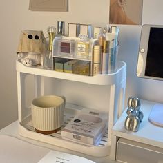 a white shelf with cosmetics and other items on it next to a computer monitor screen