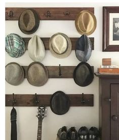 hats are hanging on the wall next to a guitar and hat rack in a living room