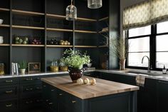 a kitchen with black cabinets and wooden counter tops, an island in front of the window