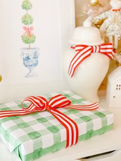 a present wrapped in green and white paper with a red bow sitting on top of it