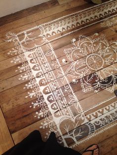 a person standing on a wooden floor with an intricate design painted on it