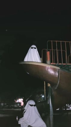 a person in a white outfit standing next to a large boat with a ghost face on it