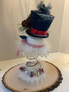 a snowman hat on top of a piece of wood with pine cones and other decorations