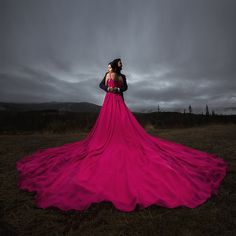 a woman in a long pink dress standing on a field