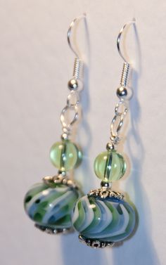 green and white glass beaded earrings with silver hooks on a white background, closeup