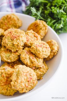 a white bowl filled with carrot patties next to some parsley on the side