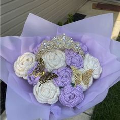 a bouquet of crocheted flowers with butterflies on them in purple paper wrapper