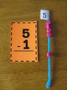 a wooden table topped with an orange and blue number sign next to a pink toothpick