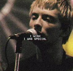 a young man singing into a microphone in front of a yellow light and black background