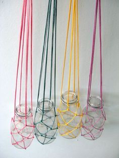 four glass vases with colorful string wrapped around them