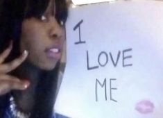 a woman holding her hand up in front of a sign that says i love me