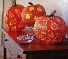 three carved pumpkins sitting on top of a wooden table next to bowls of candy