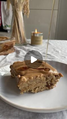 a piece of cake sitting on top of a white plate with a candle in the background