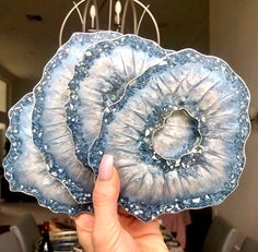 a person holding up two pieces of blue agate glass in front of a dining room table