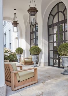 two chairs sitting on top of a patio next to potted plants in front of a building