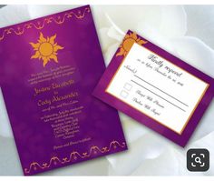 a purple and gold wedding card with an orange sun on the front is laying next to a white flower