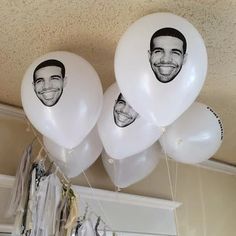 three balloons with faces on them hanging from the ceiling in front of a man's face