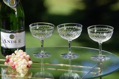 three wine glasses sitting on top of a glass table next to a bottle of wine