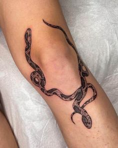 a tattoo on the leg of a woman with a snake crawling around it's arm