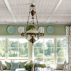 a dining room table with chairs and a chandelier in front of two windows