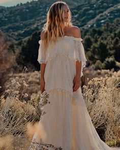 a woman standing in the desert wearing a white dress